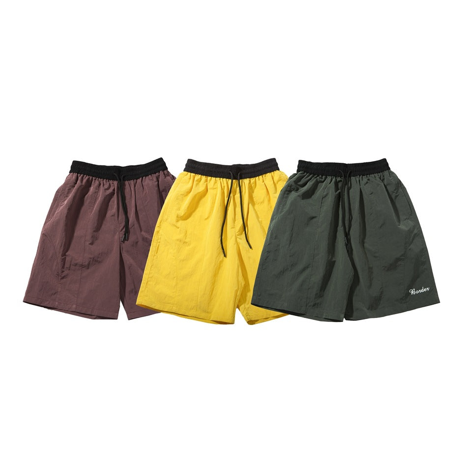 Three pairs of drawstring shorts displayed together in mauve, yellow, and dark green.