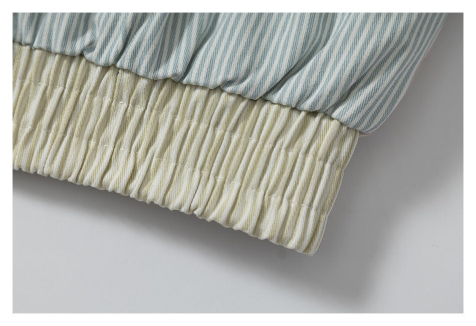 Close-up of blue-gray striped fabric gathered above a cream striped elasticized hem.