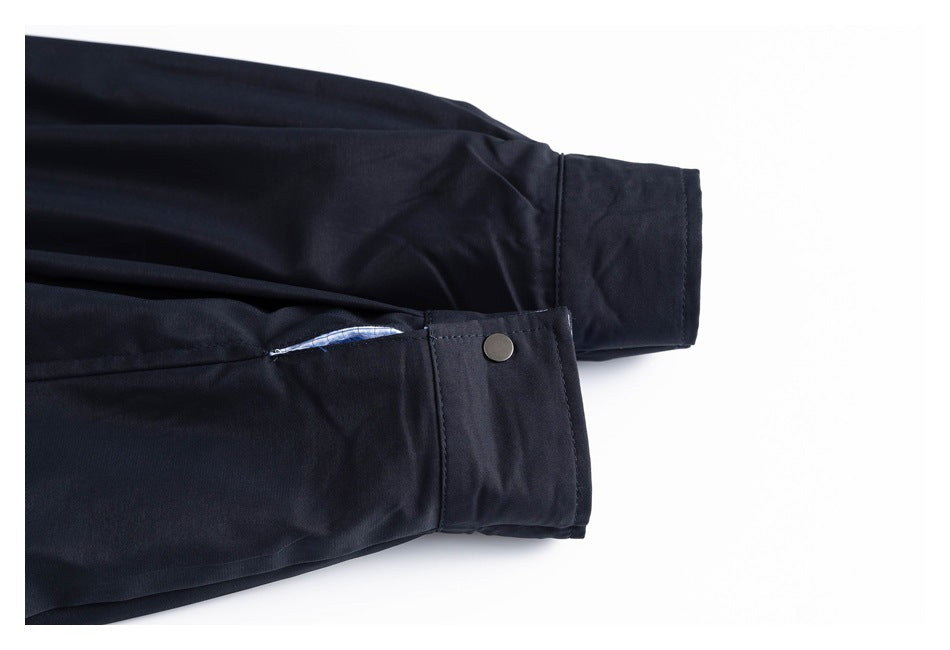 Close-up of a dark navy jacket sleeve and adjustable cuff with a metal snap.