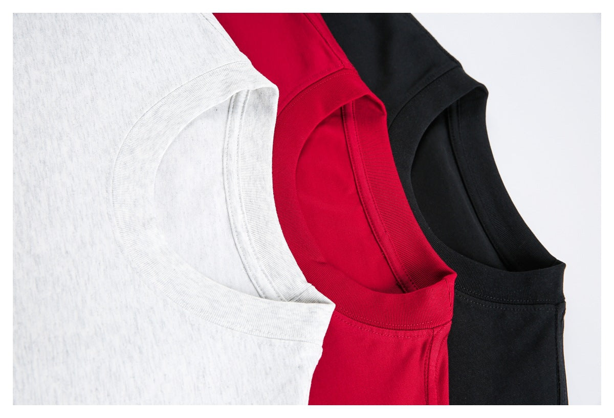 Close-up of white, red, and black crew-neck T-shirts arranged together, showing their collars and seams.