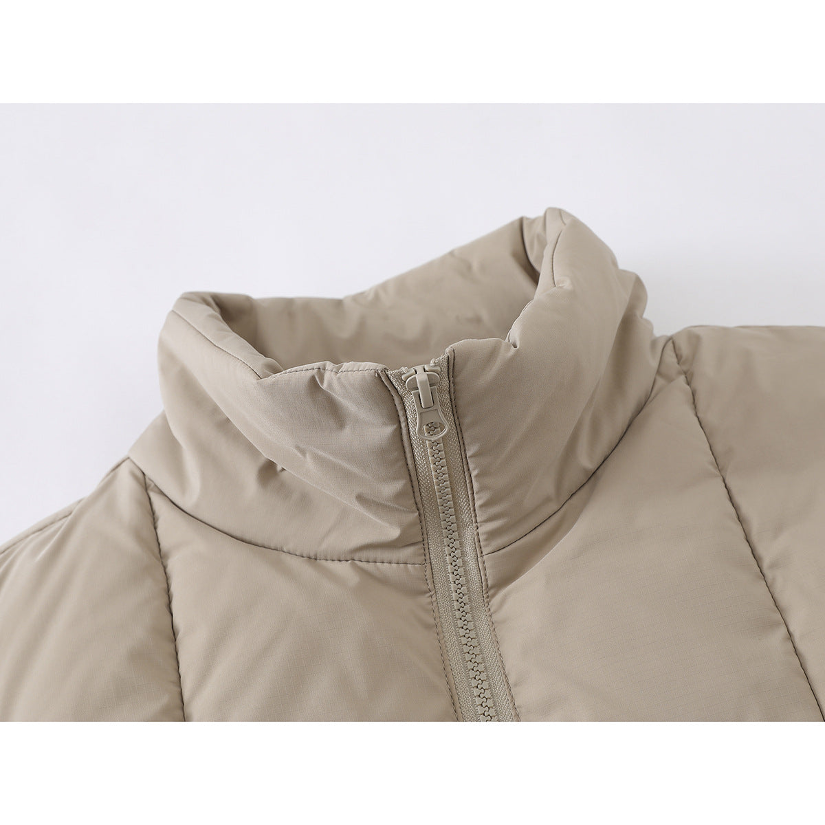 Close-up of a beige padded jacket's tall collar and front zipper.