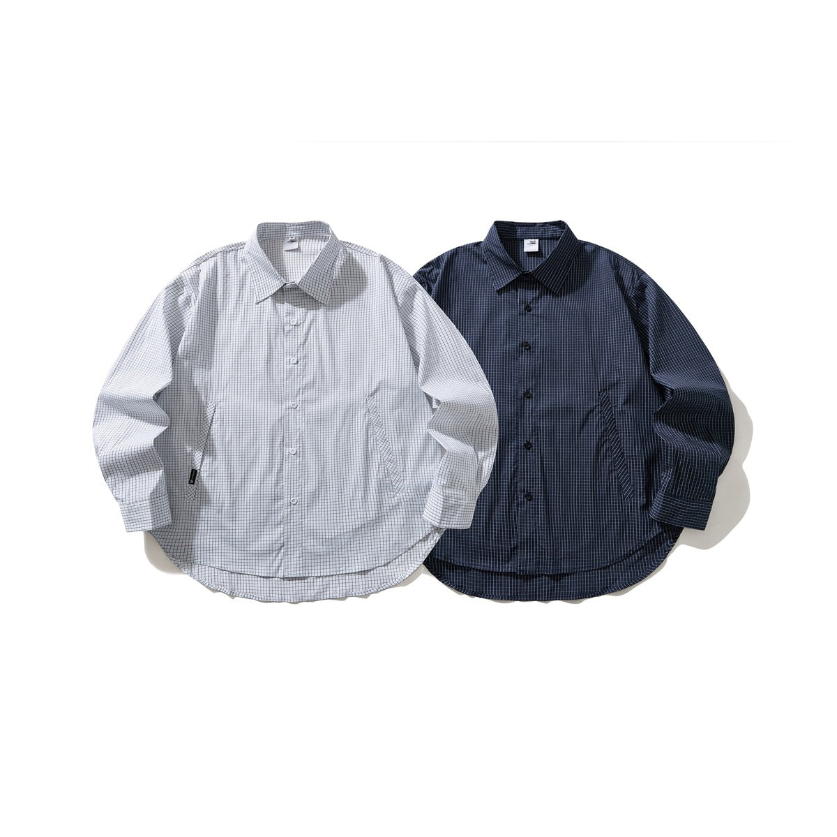 Two long-sleeve button-up shirts laid flat: one light with a fine dark check and one navy with a fine light check.
