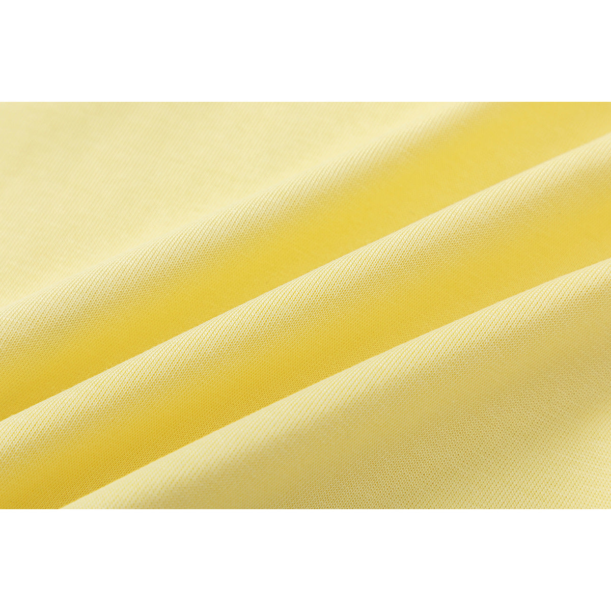 Macro view of pale yellow T-shirt fabric draped in diagonal folds.