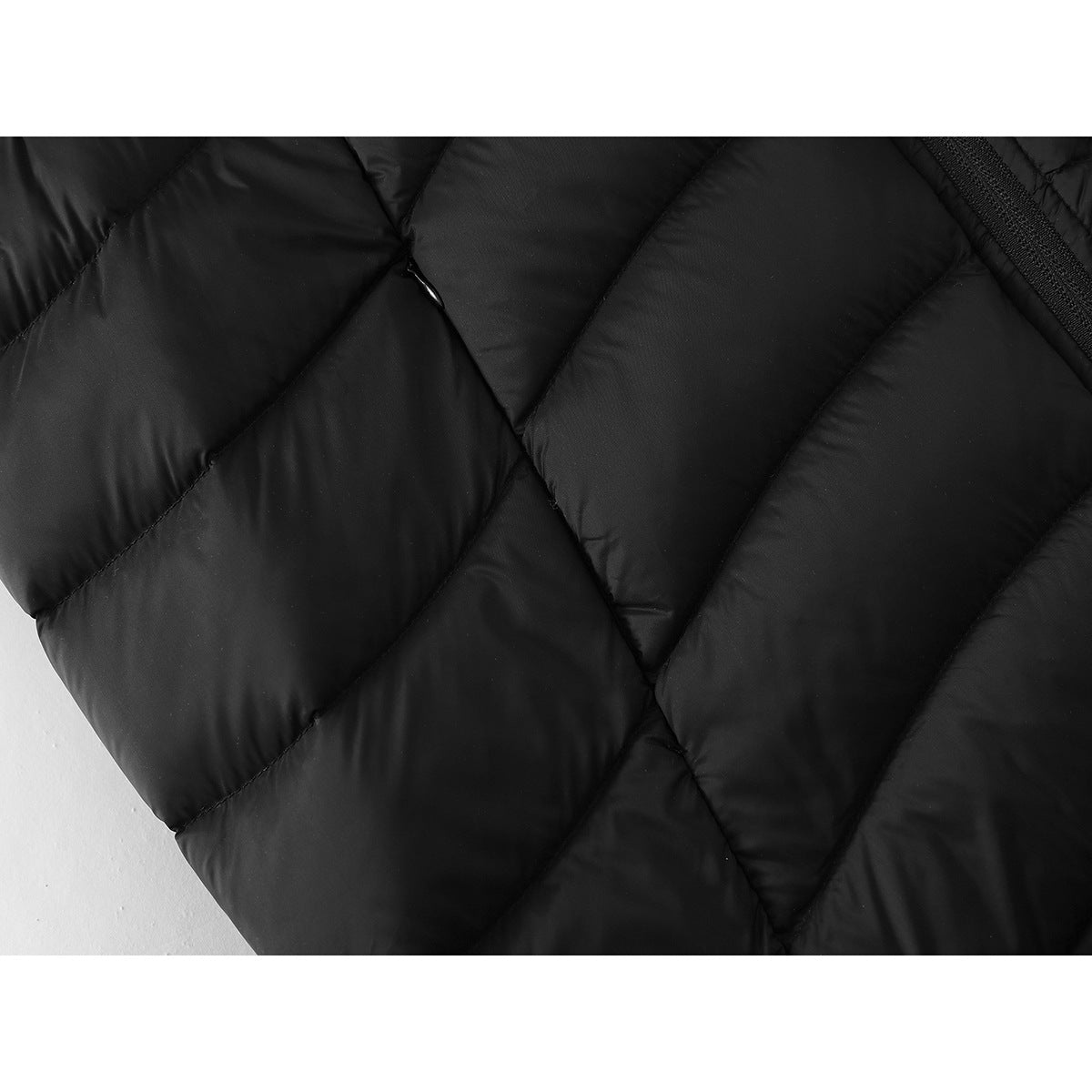 Close-up of black quilted vest fabric with diagonal stitching and padded sections.