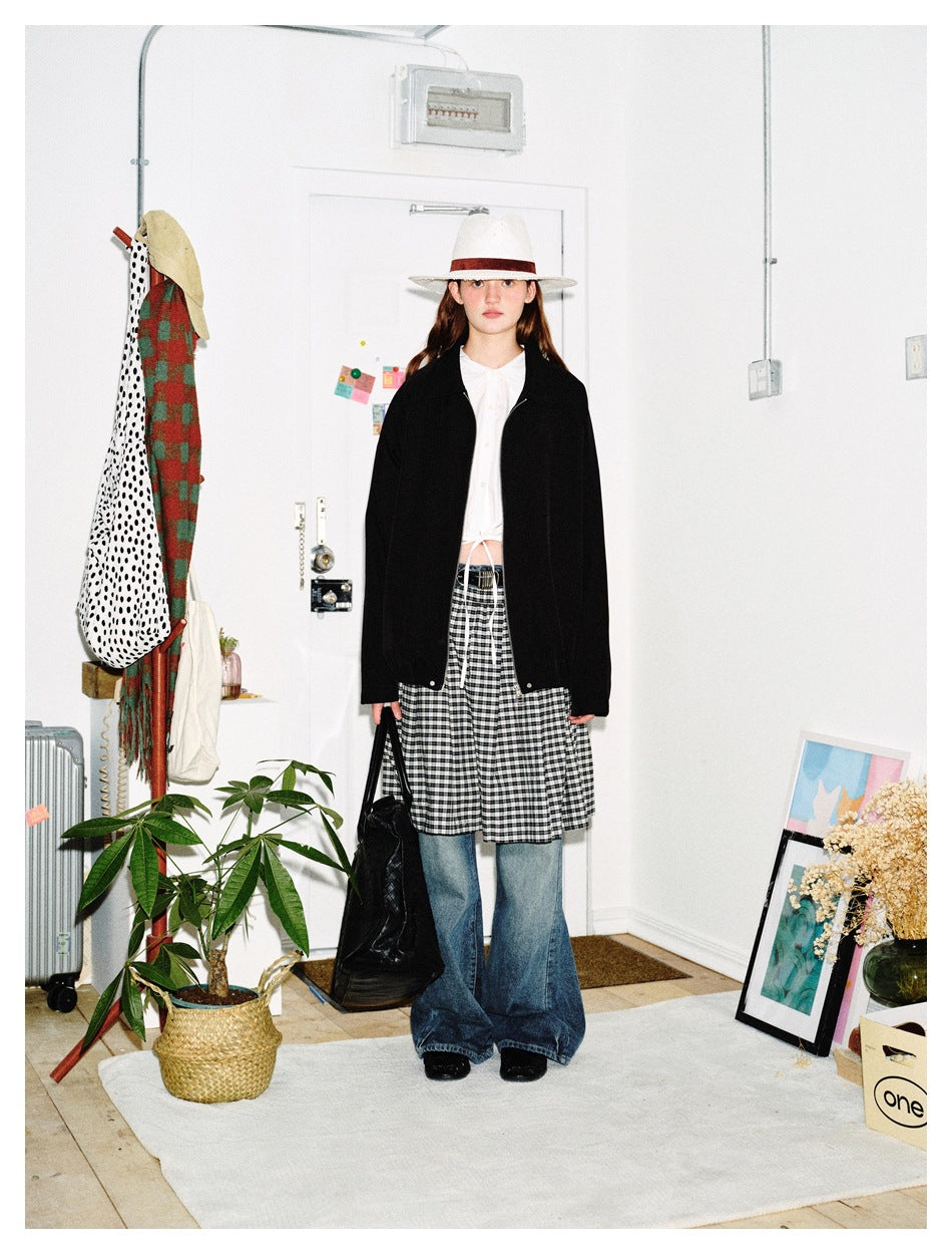 Model wearing the black jacket open over a white top, checked skirt and wide-leg jeans, front view