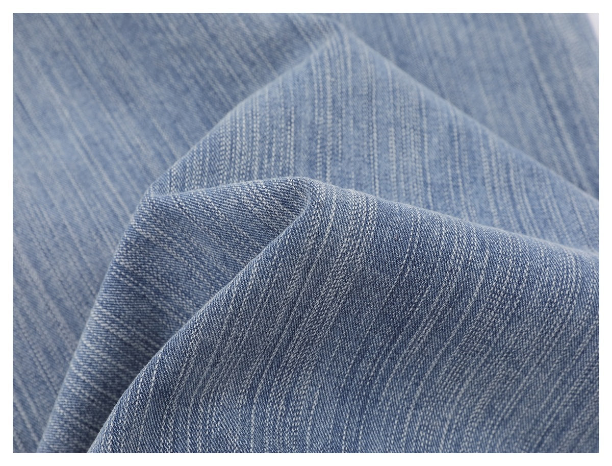 Close-up of textured blue denim folded to show its diagonal weave.