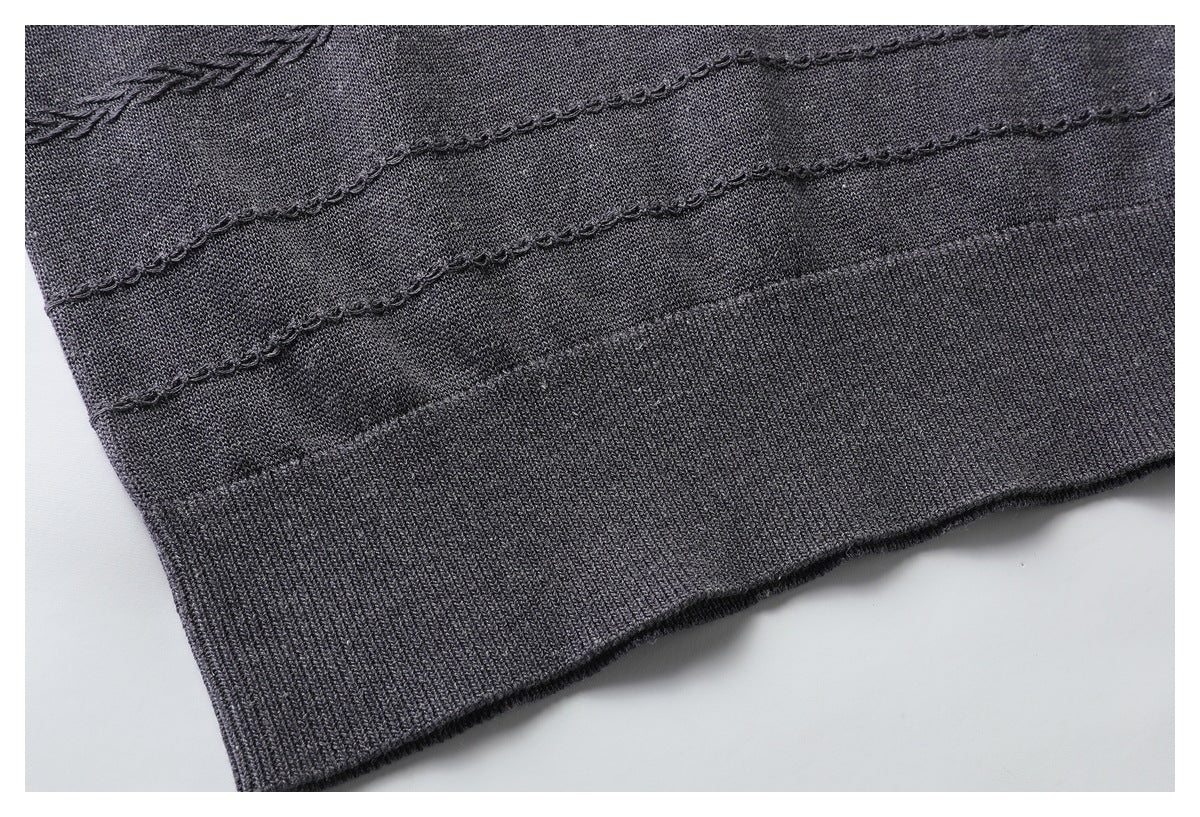 Close-up of a charcoal knit garment hem with a ribbed edge and raised decorative stitched lines.