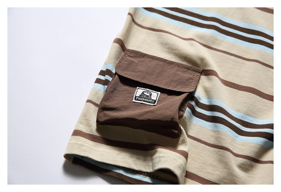 Close-up of a brown flap pocket with a small English-text patch on a beige striped T-shirt.