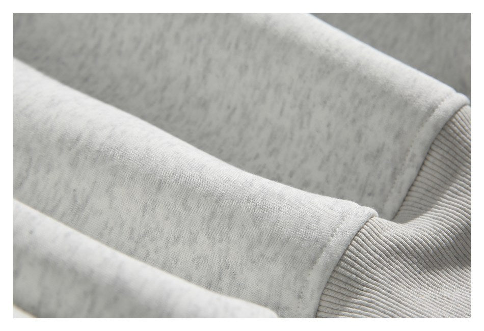 Close-up showing the heathered sleeve fabric and ribbed cuff of a light gray sweatshirt.