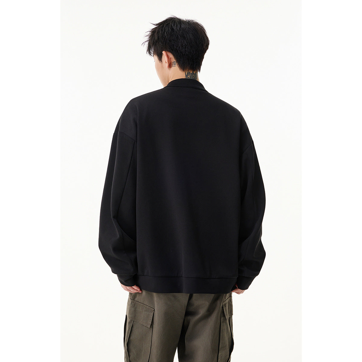 Back view of a model wearing an oversized black jacket with a ribbed hem and cuffs.