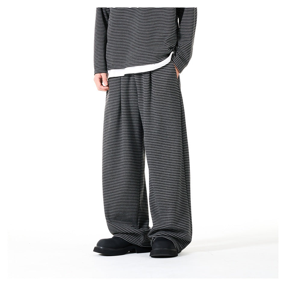 Front view of a model wearing loose black trousers with fine white horizontal stripes and a matching top.