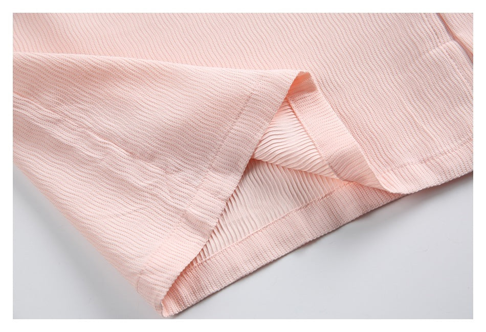 Close-up of a folded hem showing the inside of pale pink ribbed fabric and its stitching.