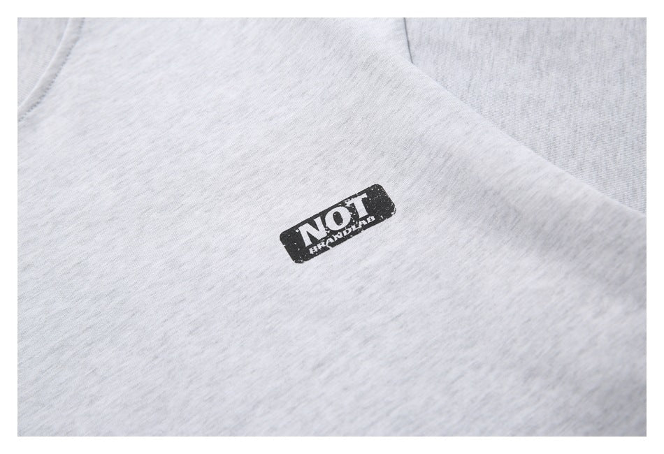 Close-up of the small distressed black logo printed on a light gray heather T-shirt.