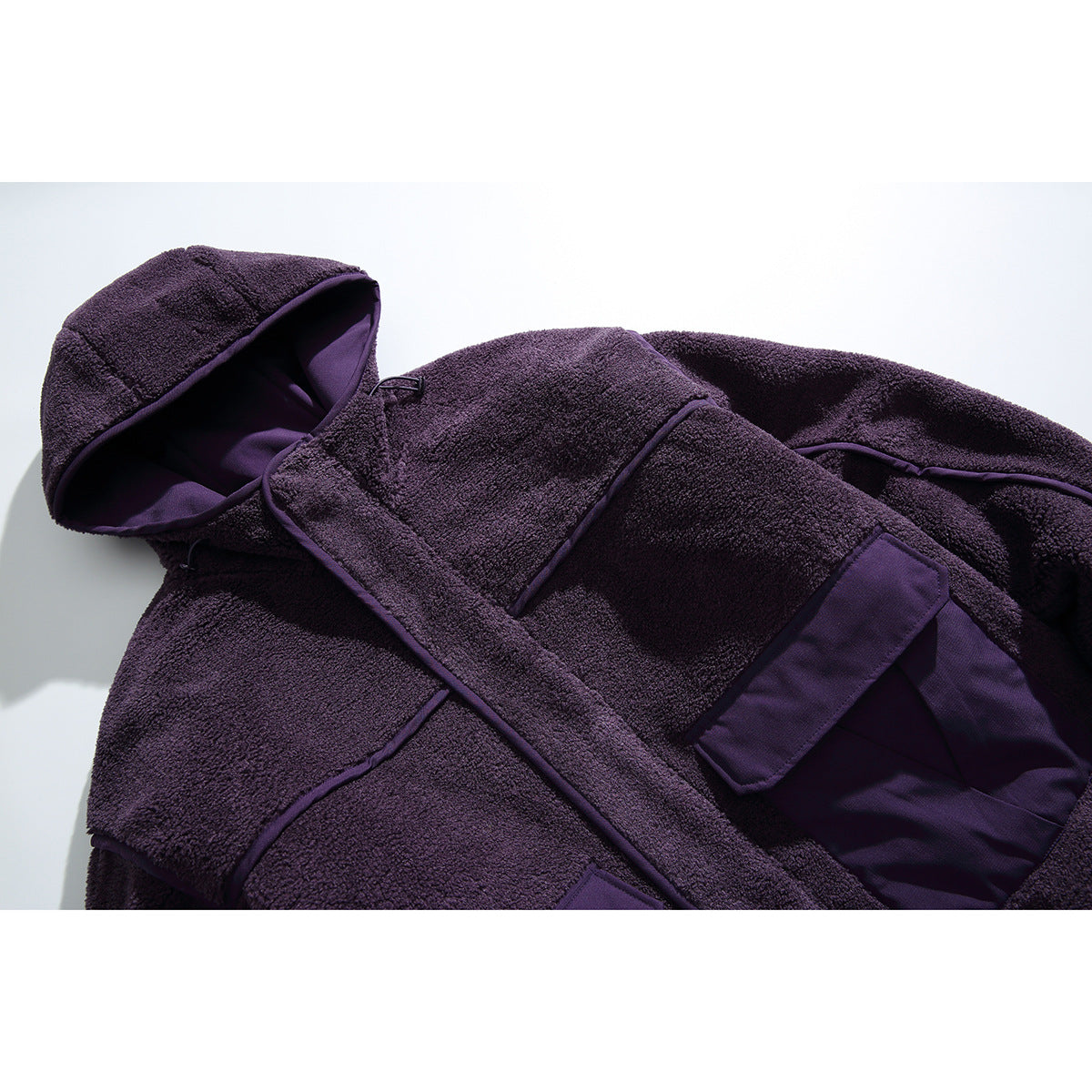 Close-up of a deep purple hooded fleece jacket, showing the hood, front panels and large flap pocket.