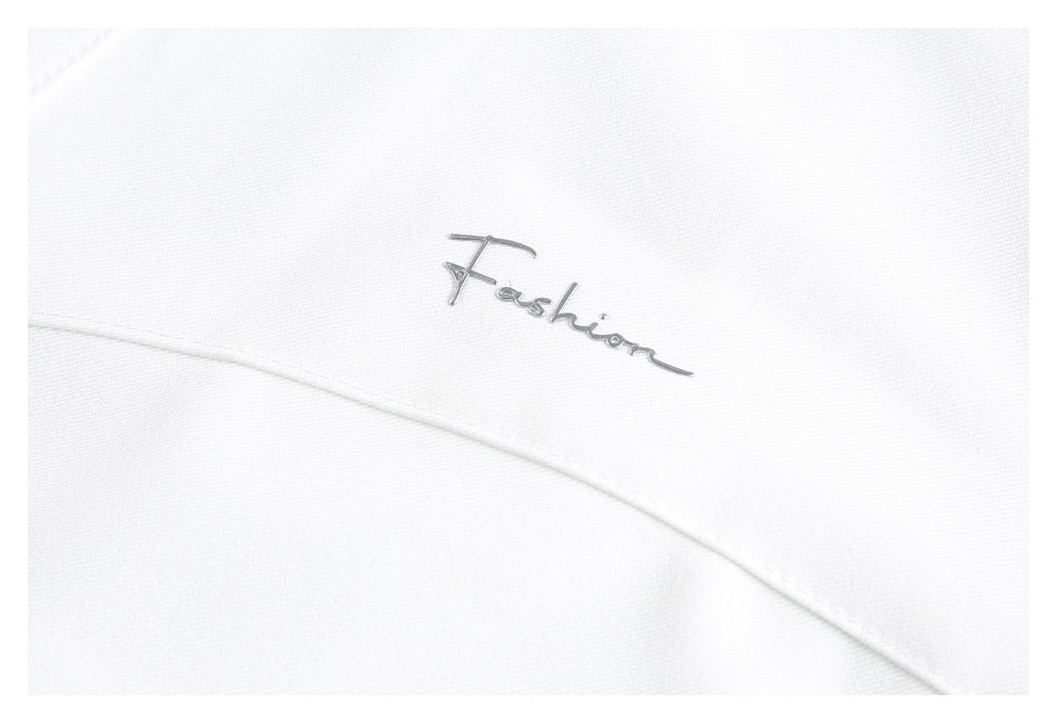 Close-up of a small silver script logo on white garment fabric.
