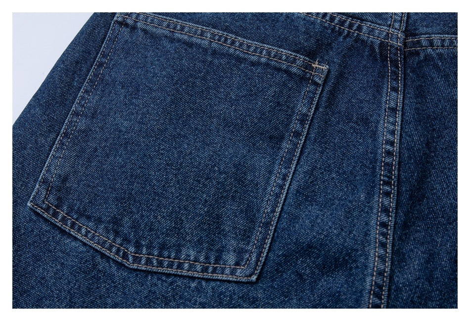 Close-up of a rear patch pocket and stitching on dark blue jeans.