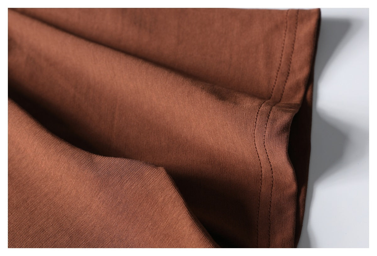 Close-up of rust-brown garment fabric and a stitched side seam.