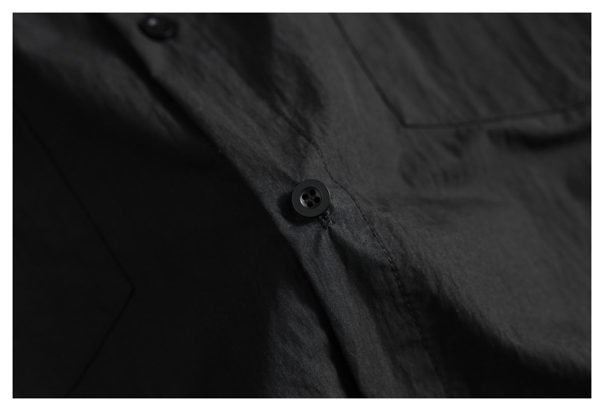 Close-up of a black shirt's front placket with a dark button and pocket edge.