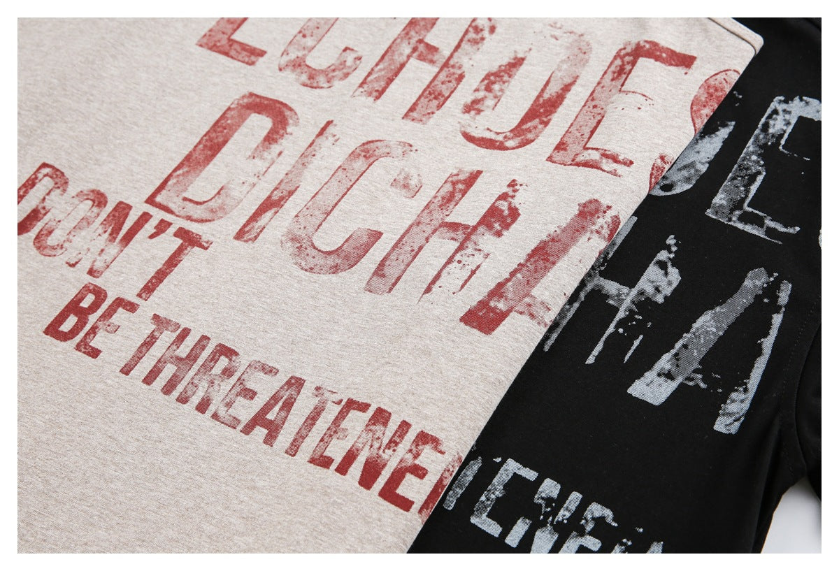 Close-up of beige and black T-shirts with distressed English lettering printed on the fronts.
