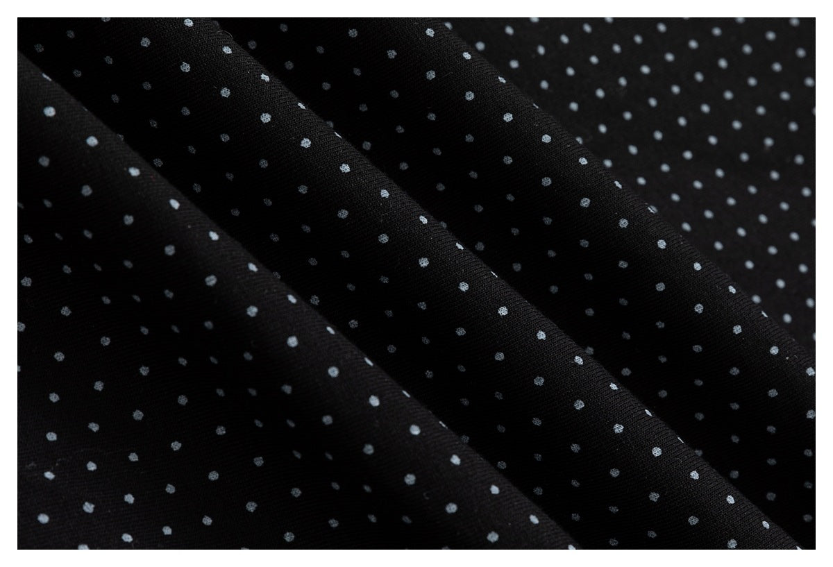 Close-up of black fabric covered in small, scattered light gray dots and soft folds.