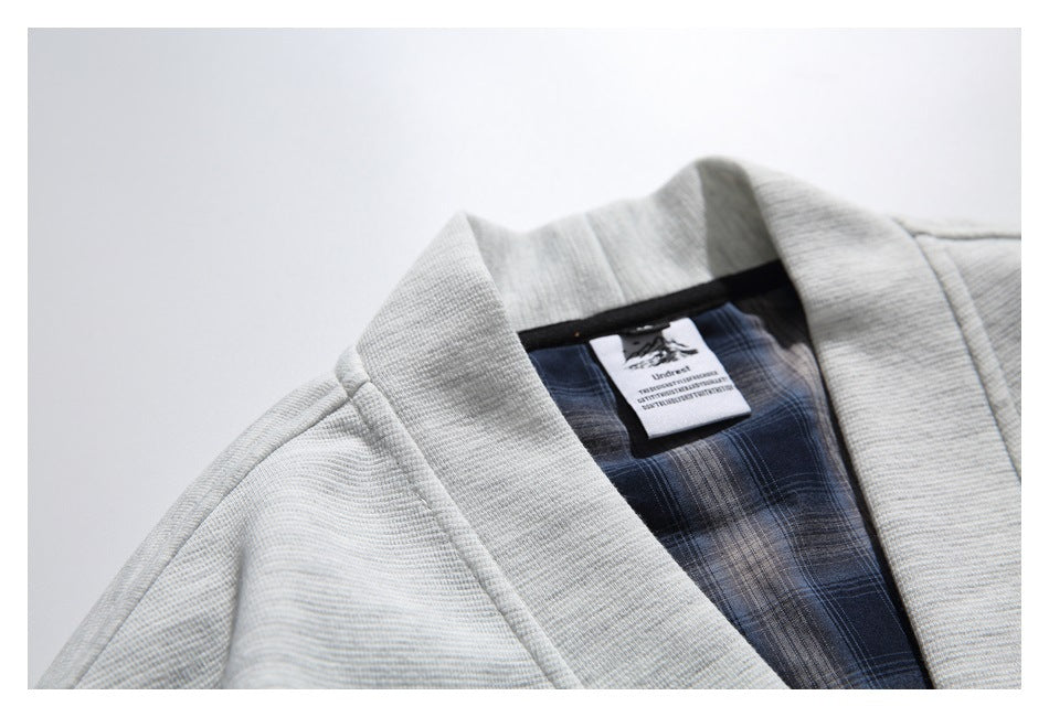 Close-up of the cardigan's shawl collar, shoulder seam, blue plaid lining, and sewn-in neck label.