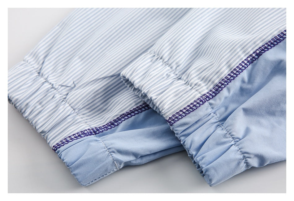 Close-up of gathered fabric edges and purple overlock seams joining striped fabric to pale blue fabric.