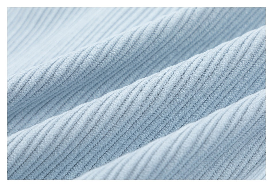 Extreme close-up of the soft, raised ribbed texture of light blue corduroy fabric.