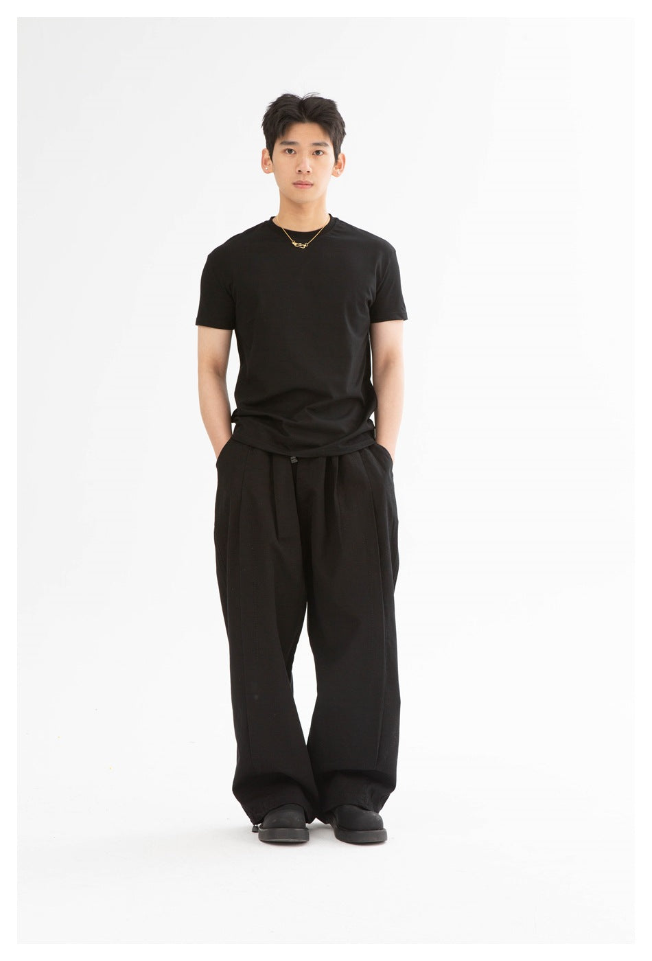Man wearing a black short-sleeve crew-neck T-shirt with wide black trousers, front view