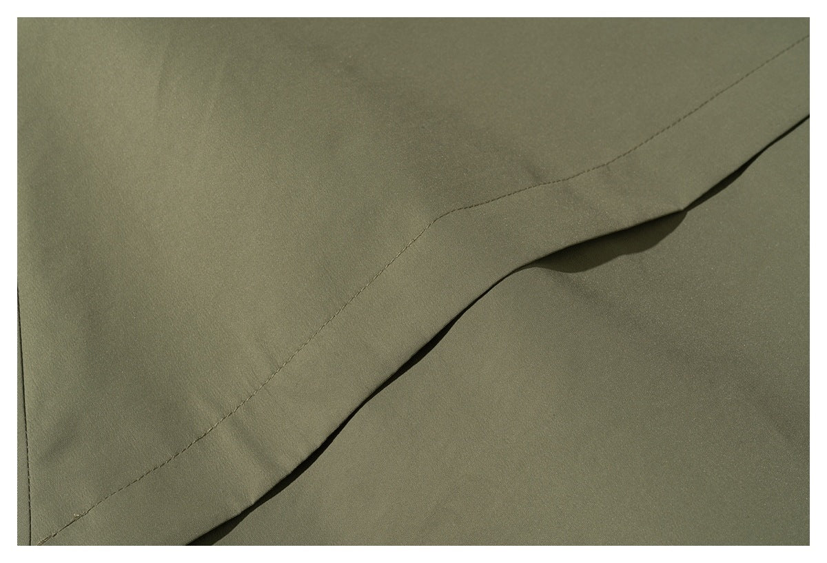Close-up of olive-green fabric showing a stitched seam and folded edge.