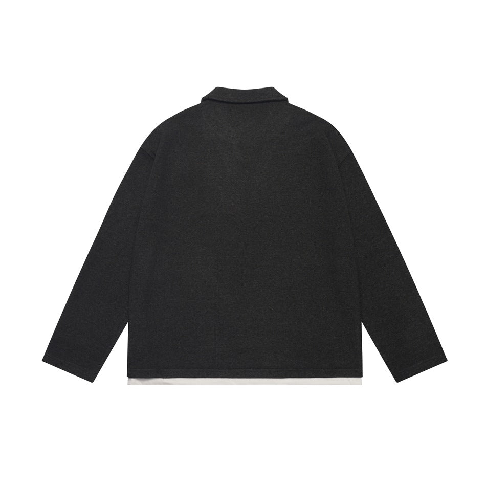 Back view of a black long-sleeve collared top with a straight hem and a narrow white layer showing below.