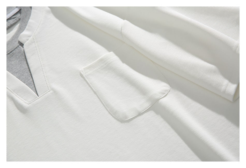 Close-up of the white top's patch pocket, sleeve, and notched neckline with a gray inner layer.