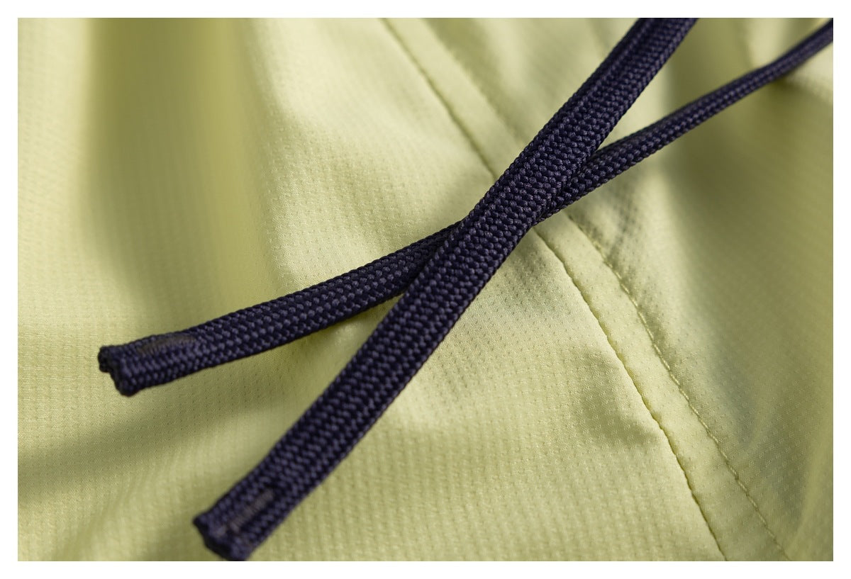 Close-up of two navy drawstrings lying across the pale yellow garment.