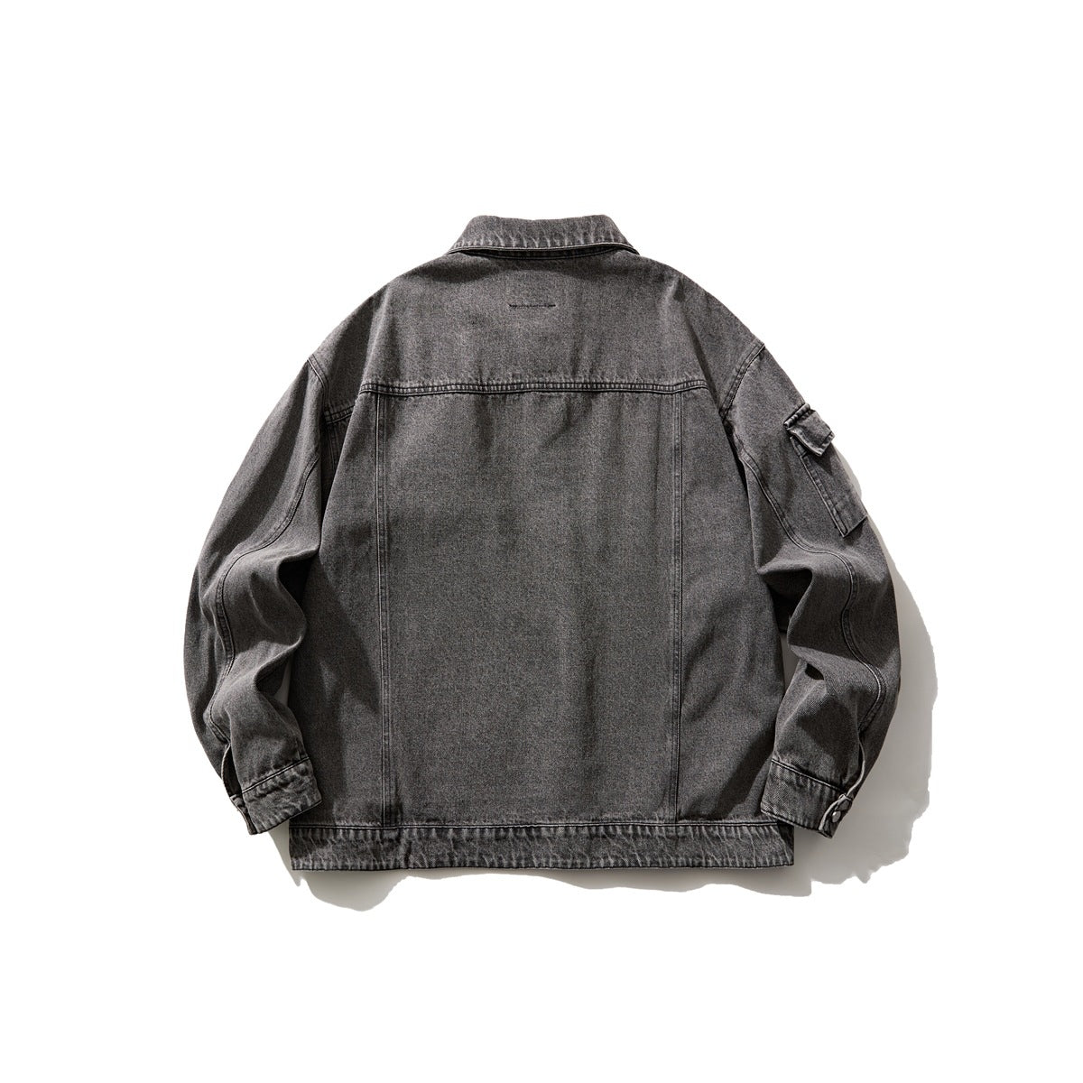 Back view of a charcoal gray washed denim jacket with a plain panel, long sleeves, and a small sleeve pocket.