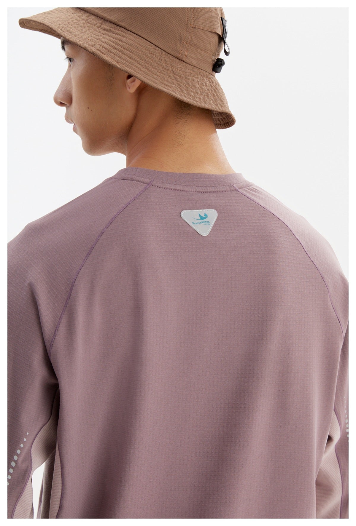 Close rear view of a person wearing a mauve long-sleeve shirt with raglan seams and a small shoulder patch.