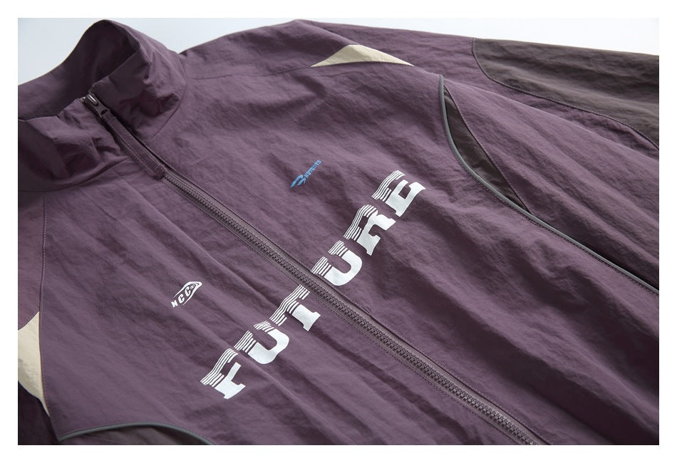 Plum jacket front close-up showing a zip, cream shoulder accent, piping, and printed graphics.