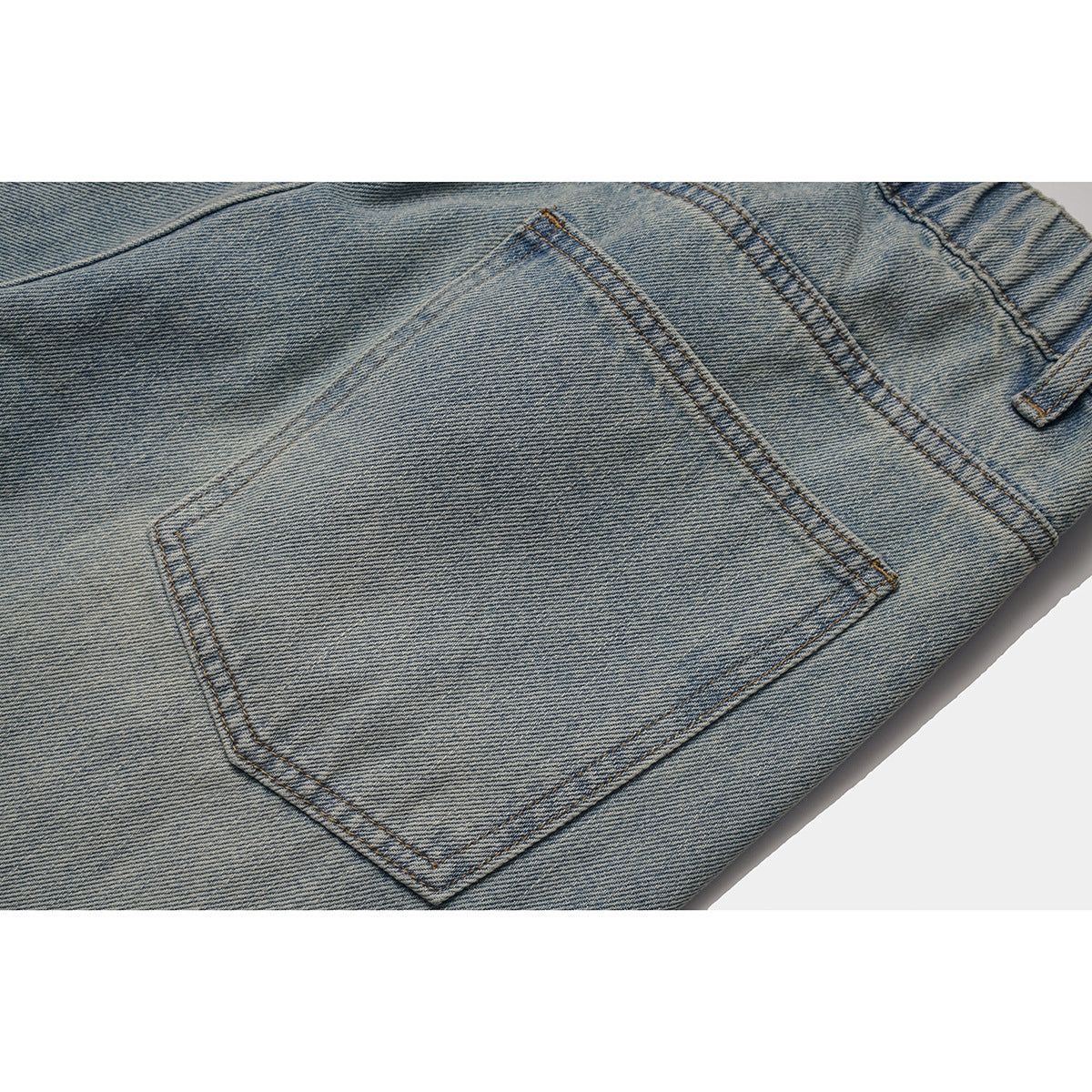 Close-up of the back pocket and stitching on light-wash jeans.