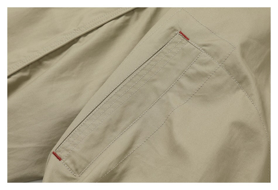 Close-up of a beige garment pocket with double stitching and small red reinforcement stitches.