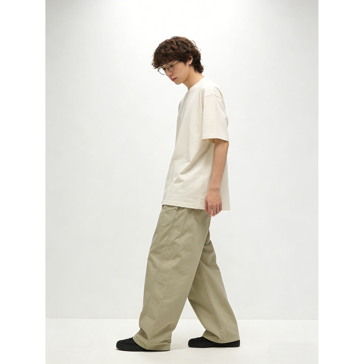 Model in profile wearing an off-white short-sleeve T-shirt and light khaki wide-leg trousers.