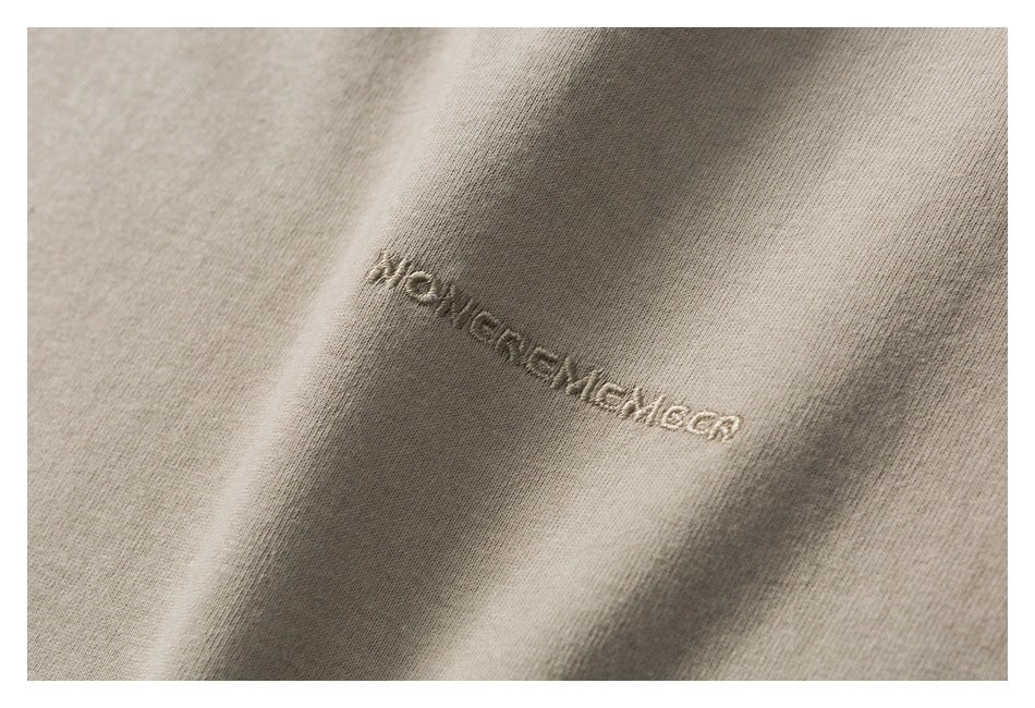 Close-up of small tonal embroidered lettering on beige fabric.