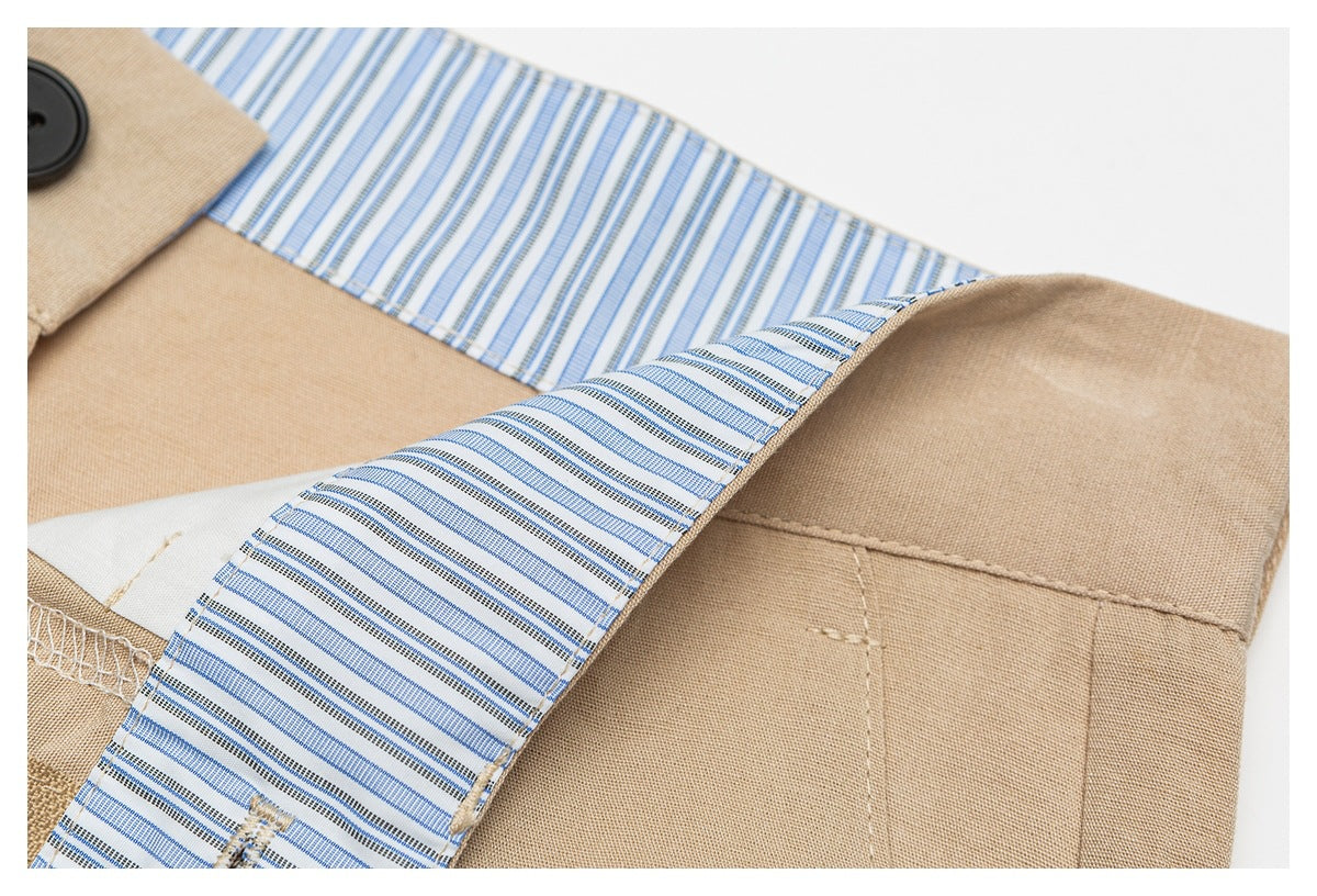 Close-up of a tan garment with blue-and-white striped inner facing, visible stitching, and a black button.