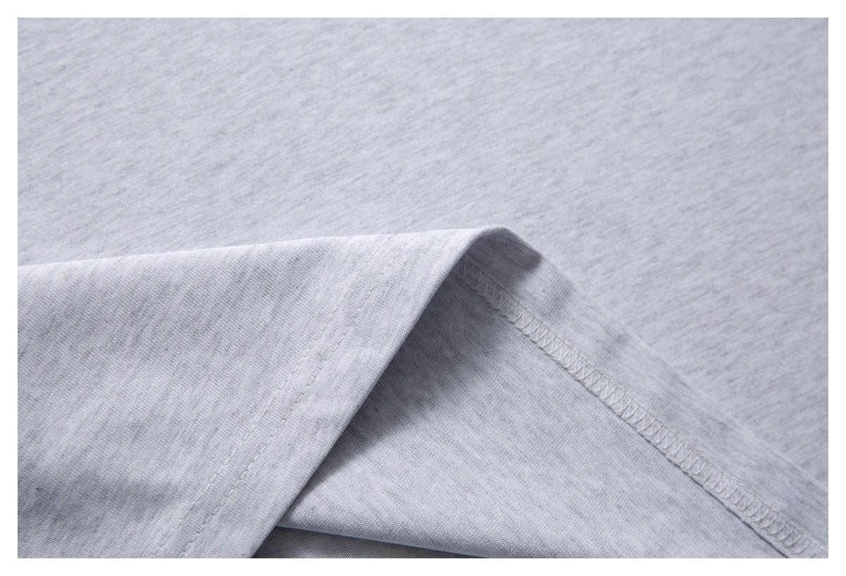 Close-up of light gray knit fabric folded to show its overlocked seam and stitching.