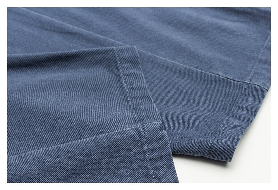 Close-up of blue-gray twill trousers showing folded fabric and stitched seams.