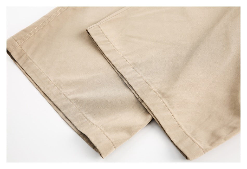 Close-up of beige trouser fabric and overlapping stitched hems.