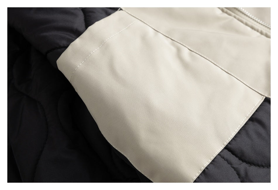Close-up of a beige jacket panel with white stitching over black quilted fabric.