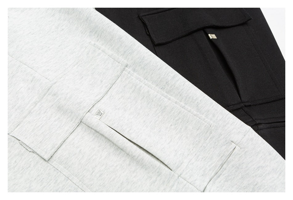 Close-up of gray and black pants showing the flap cargo pockets and small metal garment tabs.