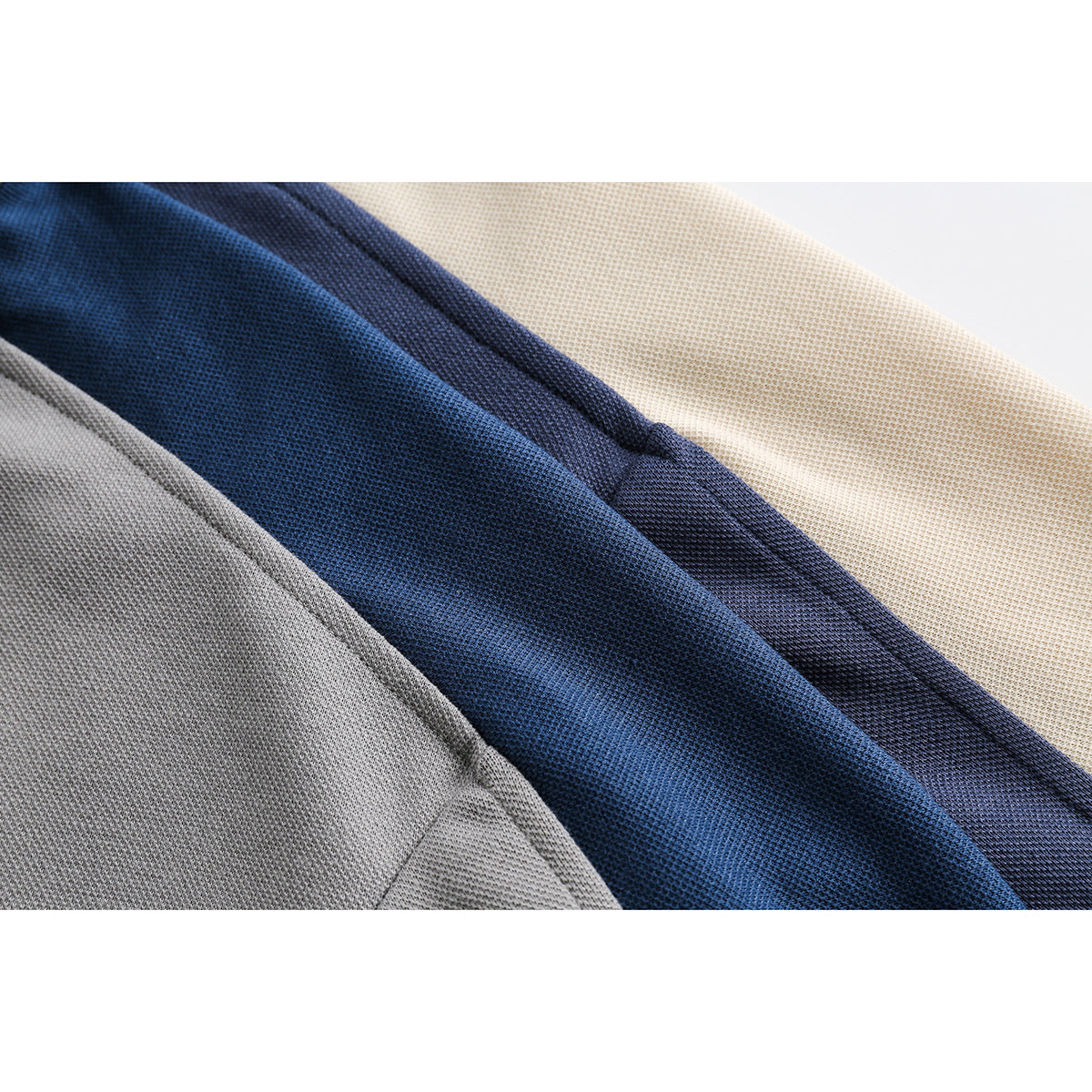 Close-up of layered gray, blue, navy, and cream knit polo fabric with visible seams.
