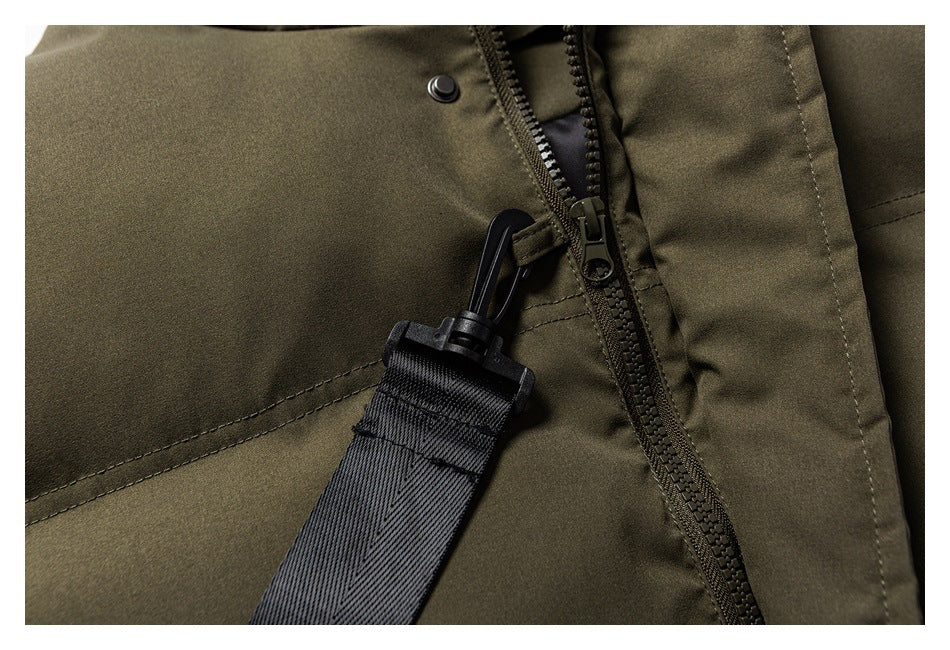 Close-up of an olive garment with a dark zipper, snap, and black webbing strap with a plastic clip.