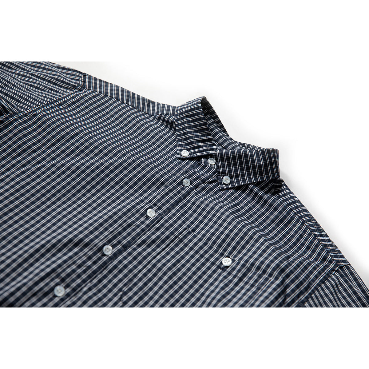 Close-up of a navy plaid button-up shirt showing its collar, white buttons and upper front.
