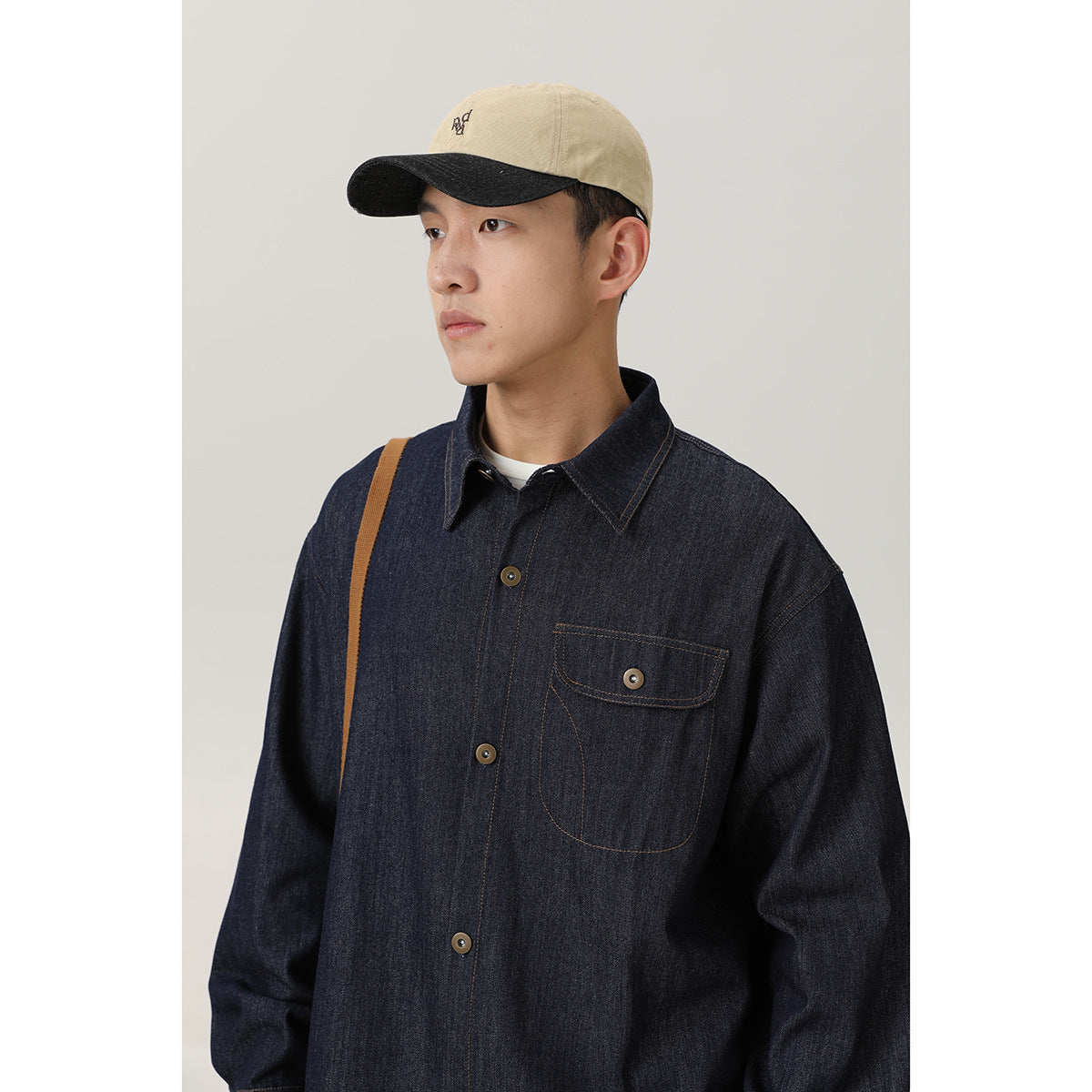 Close view of a model wearing a dark indigo shirt with a pointed collar, button front, and flap chest pocket.
