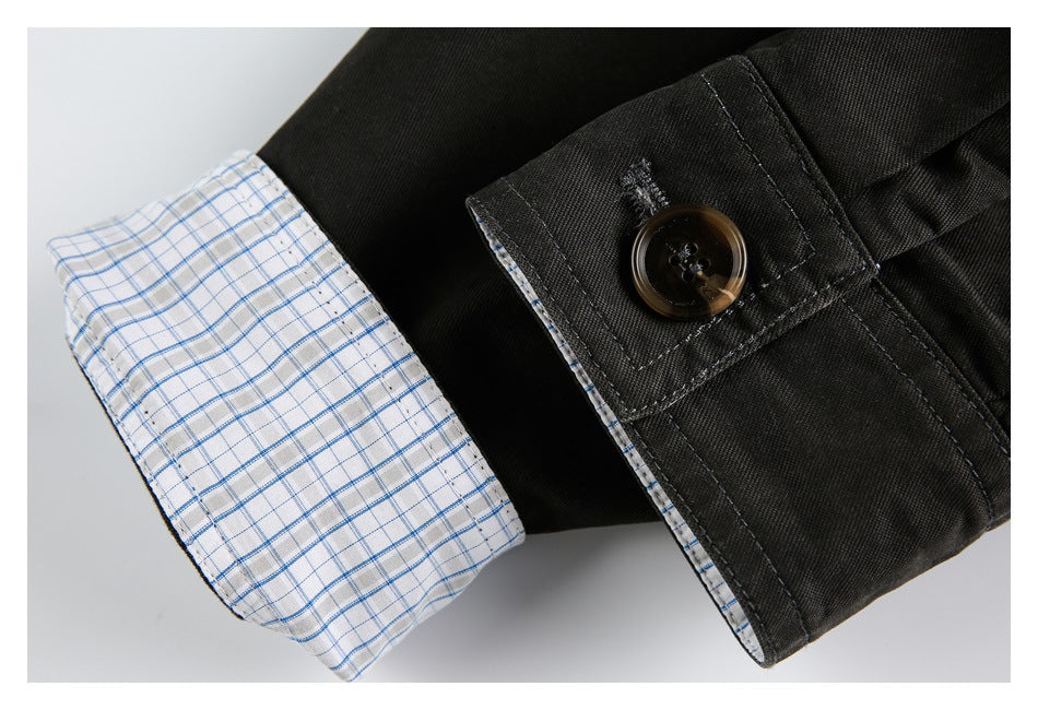 Close-up of black garment with a brown button and white lining patterned with blue checks.